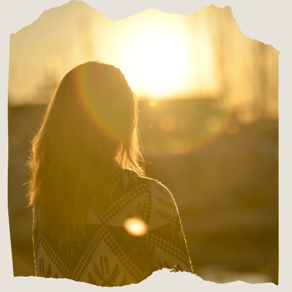 Frau von hinten schaut in die Sonne